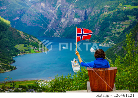 Tourist over Geirangerfjord holds norwegian flag Tourist over Geirangerfjord holds norwegian flag 120461121