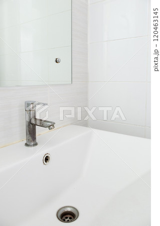The stained faucet on the white ceramic sink basin. The stained faucet on the white ceramic sink basin. 120463145