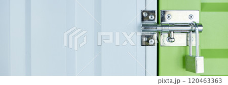 Website header shot of metal latch with lock on green door leading to self storage unit at warehouse, copy space Website header shot of metal latch with lock on green door leading to self storage unit at warehouse, copy space 120463363