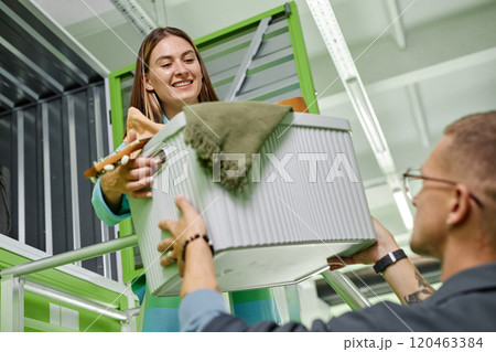 Dutch angle shot of man passing box with personal belongings to smiling girlfriend loading stuff into self storage unit in warehouse, while moving out or decluttering apartment together Dutch angle shot of man passing box with personal belongings to smiling girlfriend loading stuff into self storage unit in warehouse, while moving out or decluttering apartment together 120463384