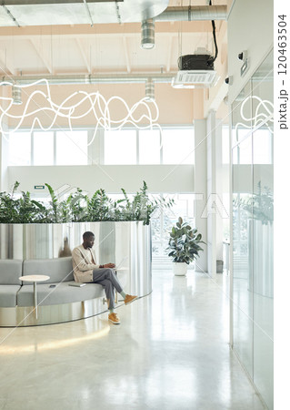 Rear view of African American male office worker entering access code on digital keypad of smart locker storing personal belongings in contemporary coworking, copy space 120463504