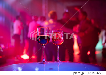 Red and white wine glasses at a lively party event 120464275