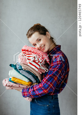 Housewife girl holds stack of clean clothes in hands after washing, drying. Housewife girl holds stack of clean clothes in hands after washing, drying. 120465749