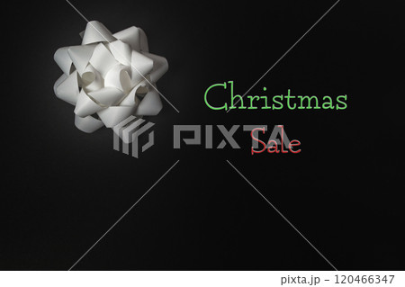 Silver bow on black background announcing Christmas Sale 120466347