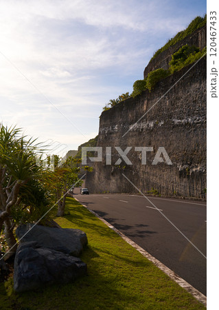 The cliff overhangs along the road to the ocean at sunset. 120467433
