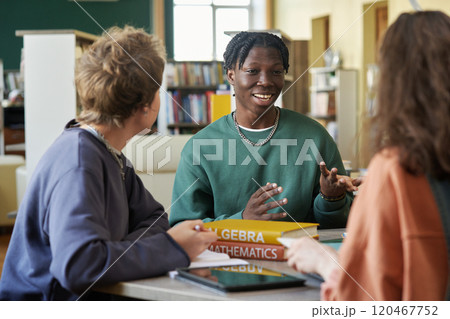 Group of diverse students in library setting, discussing algebra and mathematics books while surrounded by shelves of resources Group of diverse students in library setting, discussing algebra and mathematics books while surrounded by shelves of resources 120467752