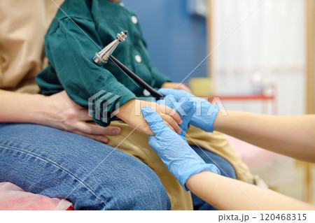 Baby and his mother are being seen by a pediatric neurologist in a modern medical clinic. Doctor conducts tests, checks the reflexes using neurological hammer of small patient. Highly qualified cure Baby and his mother are being seen by a pediatric neurologist in a modern medical clinic. Doctor conducts tests, checks the reflexes using neurological hammer of small patient. Highly qualified cure 120468315