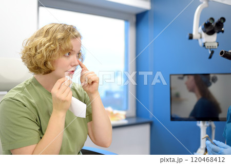 A young woman at an appointment with an otolaryngologist talks about her symptoms. A professional ENT doctor examines a patient. A young woman at an appointment with an otolaryngologist talks about her symptoms. A professional ENT doctor examines a patient. 120468412