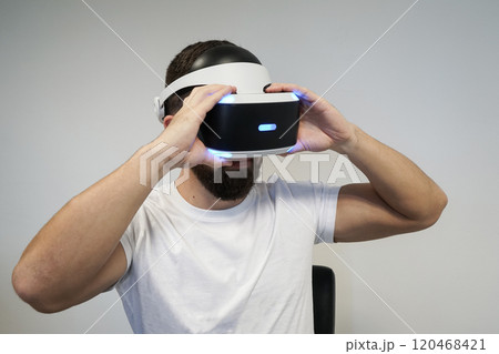 Close up of man wearing VR headset, exploring virtual worlds with blue LED lighting Close up of man wearing VR headset, exploring virtual worlds with blue LED lighting 120468421