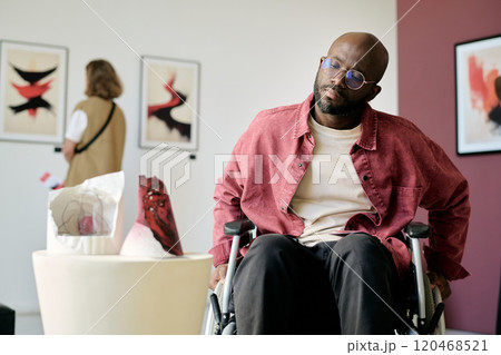 Visiting art gallery with mixed media exhibits, man in wheelchair and another visitor observing contemporary pieces in background Visiting art gallery with mixed media exhibits, man in wheelchair and another visitor observing contemporary pieces in background 120468521