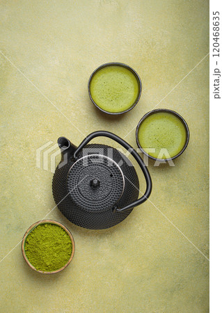Matcha tea powder and hot drink in bowls with black iron teapot on green background, Japanese tea top view Matcha tea powder and hot drink in bowls with black iron teapot on green background, Japanese tea top view 120468635