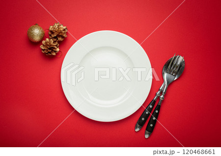 Christmas table setting with empty white plate, fir branch and golden pine cones on red background 120468661