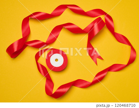 Spool of red silk ribbon on yellow background, top view Spool of red silk ribbon on yellow background, top view 120468710