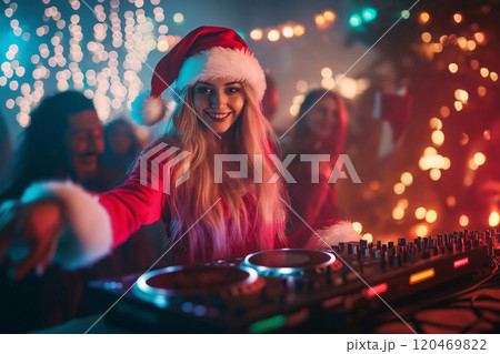 Beautiful female dj wearing a santa claus costume is mixing music at a party with festive lights in the background 120469822