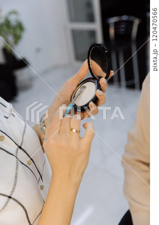 Close up of hands using a makeup brush and compact powder in a professional beauty setup Close up of hands using a makeup brush and compact powder in a professional beauty setup 120470566