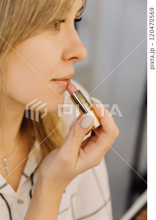 Close up of a woman applying nude lipstick for a natural and elegant makeup look Close up of a woman applying nude lipstick for a natural and elegant makeup look 120470569