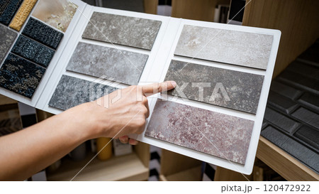Designer hand pointing at stone tile sample on display catalog Designer hand pointing at stone tile sample on display catalog 120472922