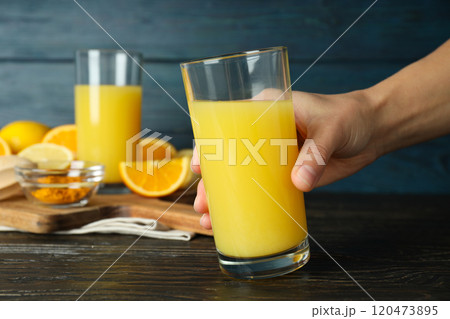 Glasses with juice, hand and ingredients on kitchen board on wooden background, close up 120473895