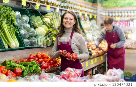 Young woman seller lays out tomatoes on counter Young woman seller lays out tomatoes on counter 120474321
