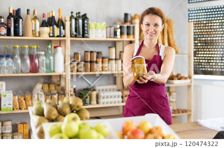 Adult woman seller offers olives in grocery store Adult woman seller offers olives in grocery store 120474322