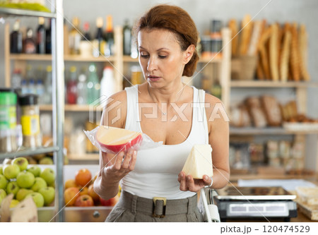 Adult woman choosing cheese in grocery store 120474529