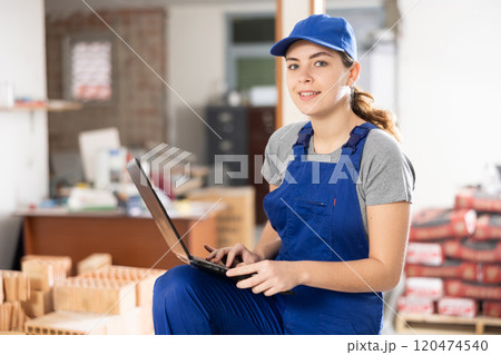Smiling female designer with laptop examining construction site Smiling female designer with laptop examining construction site 120474540
