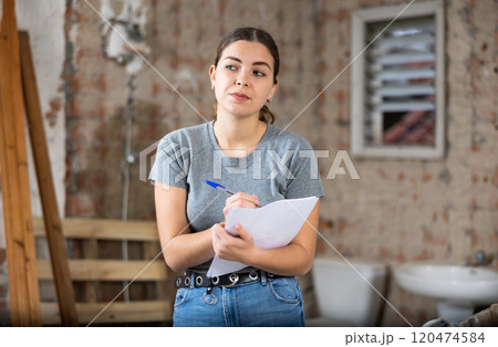 Woman making notes on indoor construction site 120474584