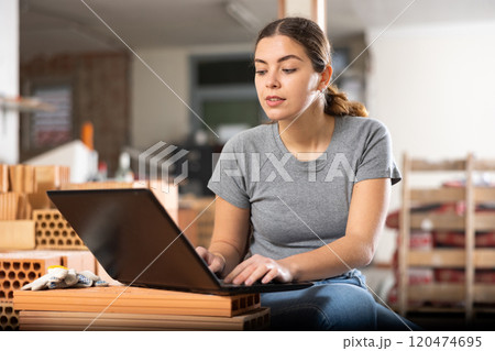Female designer working with laptop in apartment under renovation 120474695