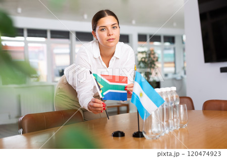 Young lady sets miniatures flags of Argentina and South Africa for international negotiations Young lady sets miniatures flags of Argentina and South Africa for international negotiations 120474923