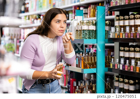 Stylish woman smelling perfume tester, choosing perfume in cosmetic shop 120475051