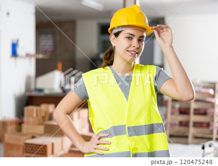 Woman builder posing on indoor construction site Woman builder posing on indoor construction site 120475248