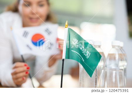 Employee of delegation prepares negotiating table - sets up flag of Saudi Aarabia and South Korea 120475391