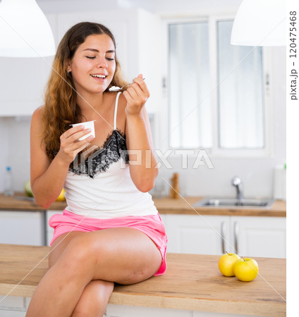 Portrait of positive girl eating yogurt at home 120475468