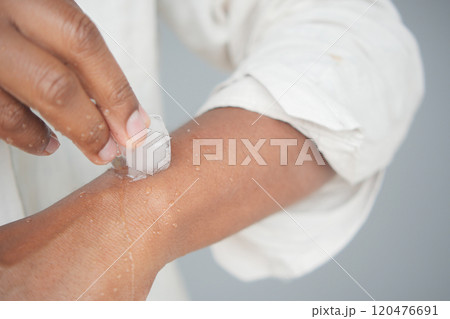 Man rubbing ice cube on his hand. Man rubbing ice cube on his hand. 120476691