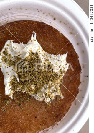 Traditional Turkish Dessert Kunefe with Clotted Cream and Crushed Pistachios.The image shows a portion of Kunefe, a traditional Turkish dessert. The knefe is topped with clotted cream Traditional Turkish Dessert Kunefe with Clotted Cream and Crushed Pistachios.The image shows a portion of Kunefe, a traditional Turkish dessert. The knefe is topped with clotted cream 120477031