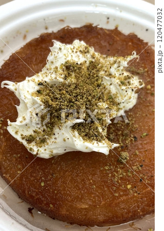 Traditional Turkish Dessert Kunefe with Clotted Cream and Crushed Pistachios.The image shows a portion of Kunefe, a traditional Turkish dessert. The knefe is topped with clotted cream Traditional Turkish Dessert Kunefe with Clotted Cream and Crushed Pistachios.The image shows a portion of Kunefe, a traditional Turkish dessert. The knefe is topped with clotted cream 120477032