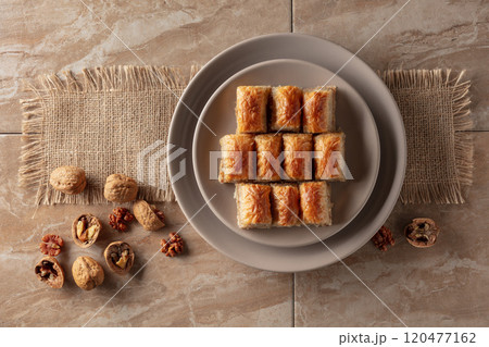 Baklava with walnuts on a beige plate. 120477162