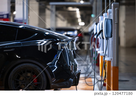 EV charger and electric car, Electric car charger station for charge ev battery, Plug for vehicle with electric engine, EV charger clean energy, Charging point at car parking lot department store. 120477180