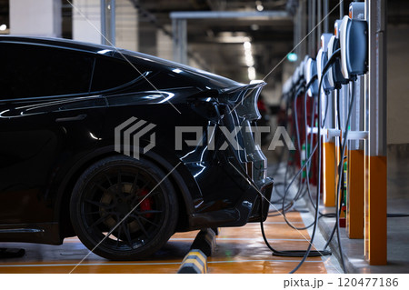 EV charger and electric car, Electric car charger station for charge ev battery, Plug for vehicle with electric engine, EV charger clean energy, Charging point at car parking lot department store. 120477186