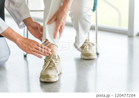足の痛みを訴える高齢者を診察する医師の手元 120477284