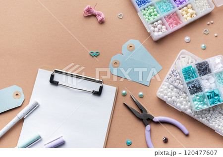 Crafting supplies arranged on a workspace with beads, tools, tags for personalized jewelry making Crafting supplies arranged on a workspace with beads, tools, tags for personalized jewelry making 120477607