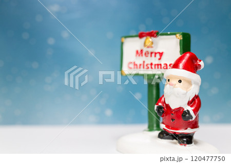 Miniature Santa Claus figurine standing next to a festive Merry Christmas sign Miniature Santa Claus figurine standing next to a festive Merry Christmas sign 120477750