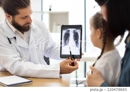 Caucasian doctor explains lung x-ray to young sick girl in clinic Caucasian doctor explains lung x-ray to young sick girl in clinic 120478683