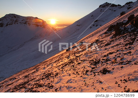 Breathtaking Rocky Mountain Slope Bathed in Morning Sunlight with Snow-Capped Peaks Nearby 120478699