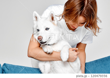 Woman Embracing Her Calm White Husky 120479356