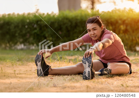 Athlete with prosthetic leg doing warm up exercise on park. Woman wearing prosthetic equipment for jogging. Athlete with prosthetic leg doing warm up exercise on park. Woman wearing prosthetic equipment for jogging. 120480548