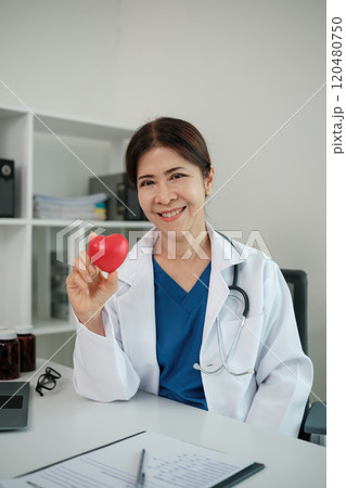 A woman doctor is holding a red heart in her hand A woman doctor is holding a red heart in her hand 120480750