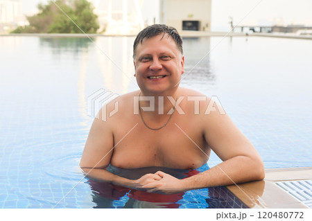 Man with wet hair stands in swimming pool of luxury hotel Man with wet hair stands in swimming pool of luxury hotel 120480772