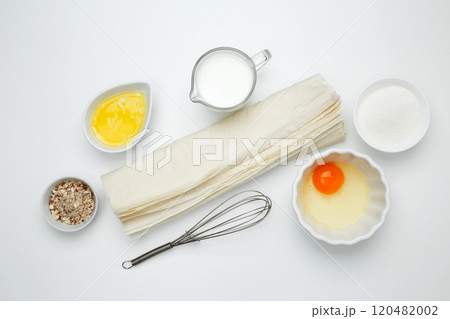 Ingredients, phyllo dough, egg, butter, nuts, and milk on a white background for baking Crinkle Cake Ingredients, phyllo dough, egg, butter, nuts, and milk on a white background for baking Crinkle Cake 120482002