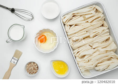 Filo dough in a baking dish near milk, eggs, butter, butter, sugar for Crinkle Cake baking Filo dough in a baking dish near milk, eggs, butter, butter, sugar for Crinkle Cake baking 120482010